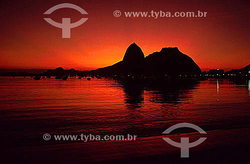  Silhouette of Sugar Loaf Mountain* at daybreak with a red sky in the background - Rio de Janeiro city - Rio de Janeiro state - Brazil  *Commonly called Sugar Loaf Mountain, the entire rock formation also includes Urca Mountain and Sugar Loaf itself  