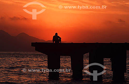  Copacabana Beach at daybreak with the silhouette of a man sitting on the pier - Rio de Janeiro city - Rio de Janeiro state - Brazil 