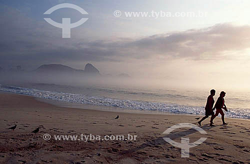  Silhouette of two persons walking at Copacabana Beach with the Sugar Loaf Mountain in the background - Rio de Janeiro city - Rio de Janeiro state - Brazil 