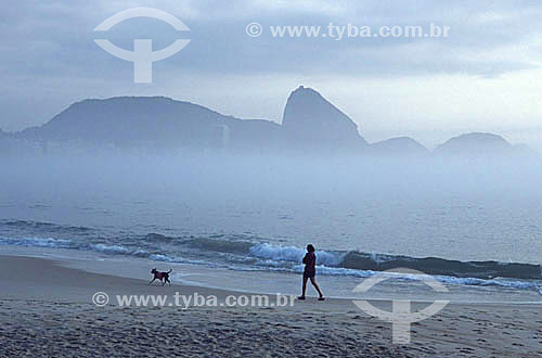  Woman and dog walking at Copacabana Beach with the Sugar Loaf Mountain in the background - Rio de Janeiro city - Rio de Janeiro state - Brazil 