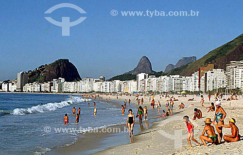  People on Copacabana Beach with part of Morro dos Dois Irmaos (Two Brothers Mountain) and Rock of Gavea* above the buildings in the background - Rio de Janeiro city - Rio de Janeiro state - Brazil  * The Rock of Gavea and the Two Brothers Mountain a 