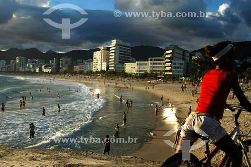  People at Ipanema Beach with buildings in the background and a man on a bycicle in the foreground - Rio de Janeiro city - Rio de Janeiro state - Brazil 