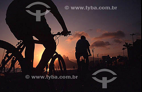  Silhouettes of cyclists and walkers on the bicycle path on Ipanema Beach at sunset - Rio de Janeiro state - Brazil 