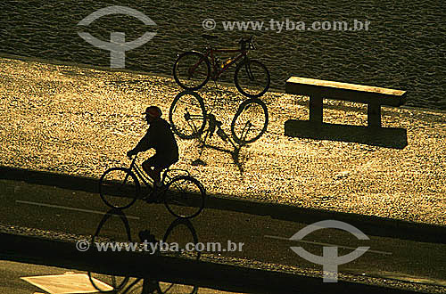  Silhouettes of a cyclist and a bicycle on the bicycle path on Ipanema Beach at sunset - Rio de Janeiro city - Rio de Janeiro state - Brazil 