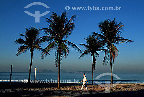  Man walking on Ipanema Promenade at dawn with four palm trees in the background - Rio de Janeiro city - Rio de Janeiro state - Brazil 