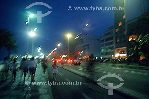 Night falls on Ipanema Beach as some people walk on the Promenade, others jog and bicycle on the bicycle path, with the lights of cars moving along Av. Vieira Souto (Vieira Souto Avenue) - Rio de Janeiro city - Rio de Janeiro state - Brazil 