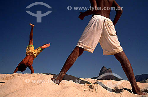  Two boys playing in the sand on Ipanema Beach with Morro Dois Irmaos (Two Brothers Mountain) in the background - Rio de Janeiro city - Rio de Janeiro state - Brazil 