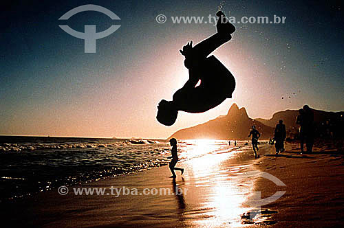  Silhouette of a person doing a somersault on Ipanema Beach at sunset with Rock of Gavea and Morro Dois Irmaos (Two Brothers Mountain)* in the background - Rio de Janeiro city - Rio de Janeiro state - Brazil  * The Gavea Rock and the Two Brothers Mou 