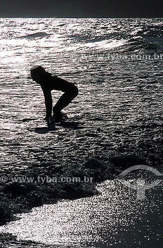  Silhouette of a woman on Ipanema Beach, highlighted by the reflection of the sun on the water - Rio de Janeiro city - Rio de Janeiro state - Brazil 