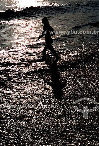  Silhouette of a woman on Ipanema Beach, highlighted by the reflection of the sun on the water - Rio de Janeiro city - Rio de Janeiro state - Brazil 
