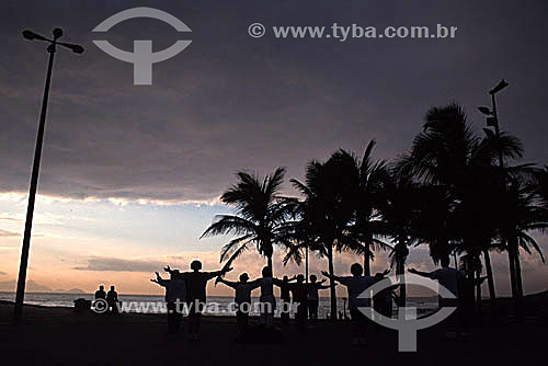  Silhouette of a group of people practicing Tai Chi Chuan at dawn on Arpoador Beach with some palm trees to the right - Rio de Janeiro city - Rio de Janeiro state - Brazil 