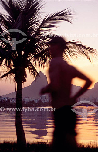  Man jogging at Lagoa Rodrigo de Freitas (Rodrigo de Freitas Lagoon)* during the sunset with coconut tree in the background - Rio de Janeiro city - Rio de Janeiro state - Brazil  * National Historic Site since 19-06-2000. 