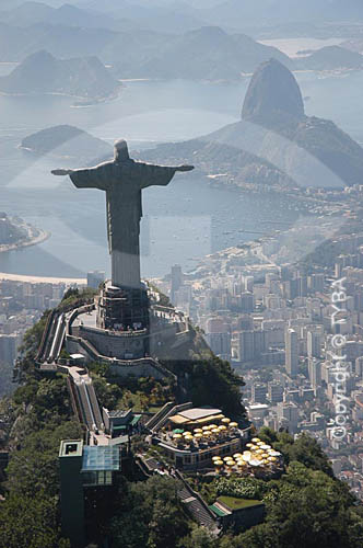  Aerial view of Cristo Redentor (Christ the Redeemer) at Morro do Corcovado (Corcovado Mountain) in Tijuca Forest, with the road and the train which ascend the mountainside, and in the background: the buildings on Botafogo Cove and the Sugar Loaf Mou 
