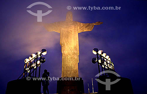  Silhouette of a couple standing in front of the brightly illuminated Cristo Redentor (Christ the Redeemer) at twilight - Rio de Janeiro city - Rio de Janeiro state - Brazil 