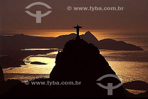  Silhouette of Cristo Redentor (Christ the Redeemer) atop Morro do Corcovado (Corcovado Mountain), with a golden sunset reflected on the water of Guanabara Bay - Rio de Janeiro city - Rio de Janeiro state - Brazil 