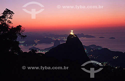  The brightly illuminated Cristo Redentor (Christ the Redeemer) with Sugar Loaf Mountain just behind it to the left, and the city of Niteroi in the background, at dawn - Rio de Janeiro city - Rio de Janeiro state - Brazil 