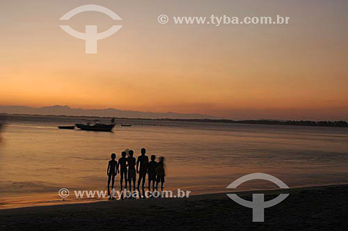  Silhouette of boys walking on the beach with boats on the sea in the background - Barra de Guaratiba Beach, at the south coast of Rio de Janeiro city - Rio de Janeiro state - Brazil 