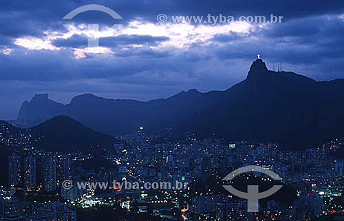  Aerial view of Rio de Janeiro at nightfall, with the buildings of the neighborhoods of Botafogo and Flamengo in the foreground, the brightly illuminated Cristo Redentor (Christ the Redeemer) at the top right, and Rock of Gavea in the background to t 