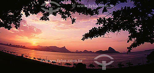  Silhouette of the mountains of Rio de Janeiro as seen through trees from the city of Niteroi, with Cristo Redentor (Christ the Redeemer) atop Corcovado Mountain in the center and Sugar Loaf Mountain to the right in the entrance to Guanabara Bay - Ri 