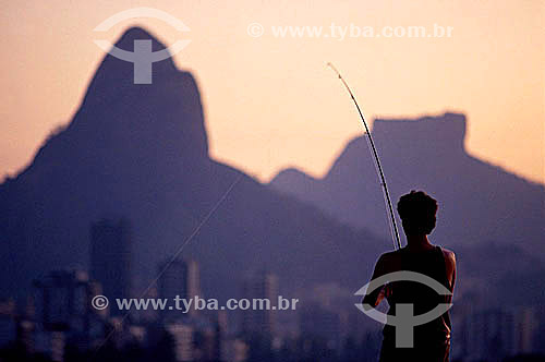  A fisherman on Lagoa Rodrigo de Freitas (Rodrigo de Freitas Lagoon) (1) , with the silhouette of Morro Dois Irmaos (Two Brothers Mountain) and Rock of Gavea (2) in the background - Rio de Janeiro city - Rio de Janeiro state - Brazil  (1) National Hi 