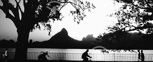  People walking at the Lagoa Rodrigo de Freitas (Rodrigo de Freitas Lagoon) (1) cycle path with Morro Dois Irmaos (Two Brothers Mountain) and Rock of Gavea (2) in the backround - Rio de Janeiro city - Rio de Janeiro state - Brazil  (1) National Histo 