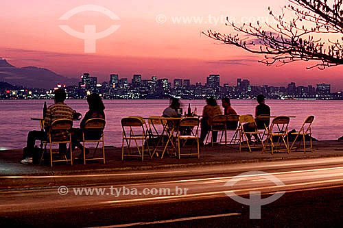  Lights of cars passing, and people enjoying the sunset and beer on Boa Viagem Beach in the city of Niteroi, with the illuminated buildings of the center of Rio de Janeiro city in the background - Niteroi city - Rio de Janeiro state - Brazil 