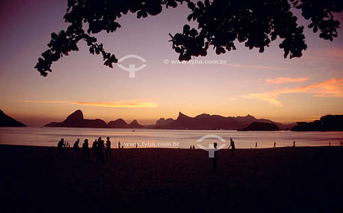  Silhouette of people on Icarai Beach at sunset with a view of Rio de Janeiro in the background showing, from left to right:  the Sugar Loaf Mountain, the Morro dos Dois Irmaos (Two Brothers Mountain), the Gavea Rock, the Cristo Redentor (Christ the  