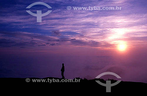  Silhouette of a man viewing the sunset and a blanket of clouds below Serra dos Orgãos (Orgaos Mountain Range) - Teresopolis city - Rio de Janeiro state - Brazil 