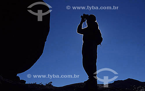 Silhouette of park ranger scanning the Vale dos Lírios (Valley of Lilies) with binoculars in Itatiaia National Park* - Rio de Janeiro state - Brazil  *This is the oldest National Park in Brazil, created in 1937. It is located among the slopes and pe 
