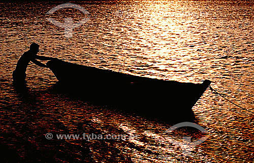  Man with his boat on Praia do Siqueira (Siqueira Beach), highlighted by the golden reflection of sunset on the water - Cabo Frio city - Costa do Sol (Sun Coast) - Regiao dos Lagos (Lakes Region) - Rio de Janeiro state - Brazil 