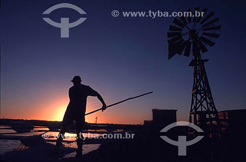  Silhouette of a worker in a salt flat at sunset with a windmill typical to the region in the background - Arraial do Cabo city - Costa do Sol (Sun Coast) - Região dos Lagos (Lakes Region) - Rio de Janeiro state - Brazil 