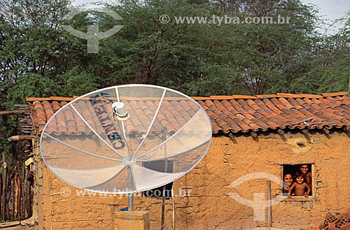  Family at the window of a clay house with a satellite antenna in the foreground - Areia Branca city - Mossoro - Rio Grande do Norte state - Brazil 
