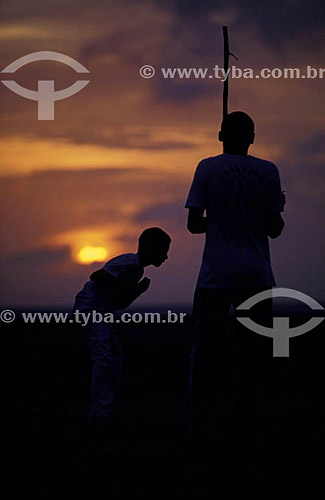  Silhouette of men playing capoeira at Jericoacoara beach at sunset - Ceara state - Brazil 