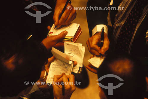  Economy - detail of hands of executives making calculations in small notebooks 