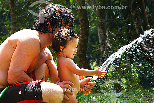  Father playing with daughter with hose 
