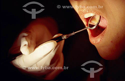  Dental health - Hand with rubber glove and dentist`s mirror tool 