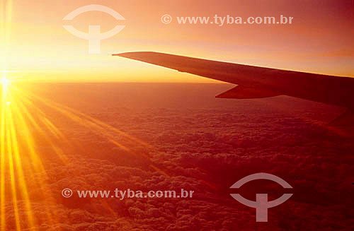  Airplane wing by sunset with clouds below it 