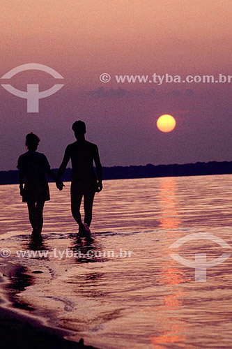  Couple walking hand in hand at the beach at sunset 