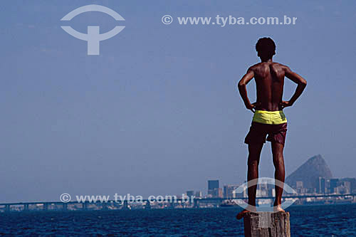  Boy in front of Guanabara Bay, with the Rio-Niteroi Bridge and the Sugar Loaf in the background - Rio de Janeiro city - Rio de Janeiro state - Brazil 