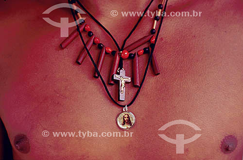  Pataxo indian mixing necklaces of his own culture (indigenous craft) and of the Catholic religion, with a crucifix and an image of Jesus Christ - 