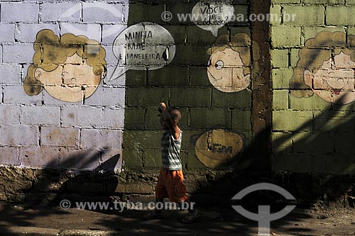  Subject: Child ( boy ) in front of a wall of brick with painting as comics next to the Cooperative Paneleiras de Goiabeiras Velha / Place: Vitoria - Espirito Santo state - Brazil / Date: March 2008 