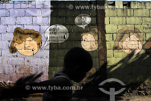  Subject: Silhouette of a child ( boy ) in front of a wall of brick with painting as comics next to the Cooperative Paneleiras de Goiabeiras Velha / Place: Vitoria - Espirito Santo state - Brazil / Date: March 2008 
