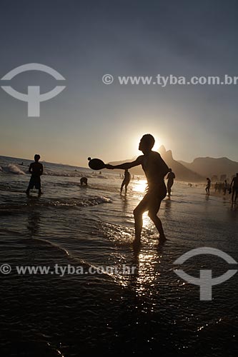  Subject: Man playing Frescobol (kind of racketball played mainly on the beach) during sunset at Ipanema Beach with Morro Dois Irmãos (Two Brothers Mountain)  on the background  / Place:  Rio de Janeiro city - Rio de Janeiro state - Brazil  / Date: 2 
