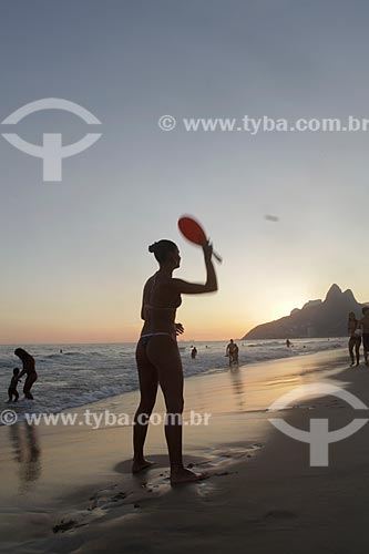  Subject: Woman playing Frescobol (kind of racketball played mainly on the beach) during sunset at Ipanema Beach with Morro Dois Irmãos (Two Brothers Mountain)  on the background  / Place:  Rio de Janeiro city - Rio de Janeiro state - Brazil  / Date: 
