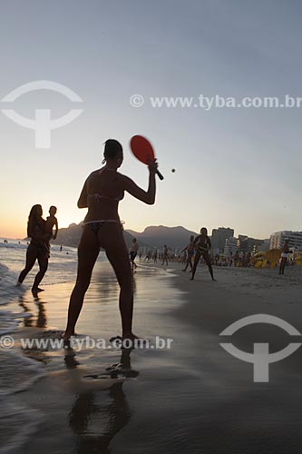  Subject: Woman playing Frescobol (kind of racketball played mainly on the beach) during sunset at Ipanema Beach with Morro Dois Irmãos (Two Brothers Mountain)  on the background  / Place:  Rio de Janeiro city - Rio de Janeiro state - Brazil  / Date: 