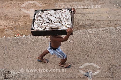  Subject: Man carrying a wood box of fish at the port of Manaus 