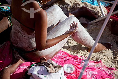  Woman applying sunscreen on her skin at Arpoador Beach  - Rio de Janeiro city - Brazil