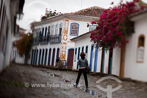  Subject: Tourist walking by a street with the paving known as pe de moleque surrounded by the colonial houses / Place: Paraty city - Rio de Janeiro state (RJ) - Brazil / Date: 07/2011 