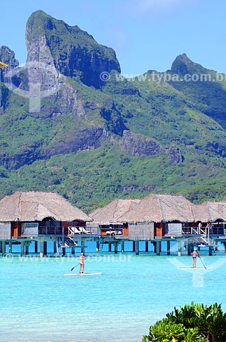  Subject: Couple practicing Paddle Surf with resort bungalows and Otemanu Mountain in the background / Place: Bora Bora Island - French Polynesia - Oceania / Date: 10/2012 
