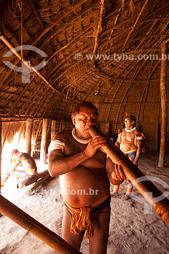  Upper Xingus Indigenous leader Aritana Yawalapiti playing the Urua flute inside the maloca reserved to men - Casa dos Homens -  during the Kuarup ceremony - this years ceremony in honor of the anthropologist Darcy Ribeiro - Photo Licensed (Released   - Gaucha do Norte city - Mato Grosso state (MT) - Brazil